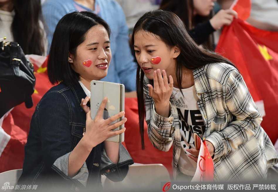 终场哨响后，获得里约奥运会参赛资格的中国女篮队员们兴奋地围在一起，手拉手向看台上始终不离不弃的中国球迷鞠躬致谢。背景是巨大的记分牌，见证了这一属于中国篮球的荣耀时刻。