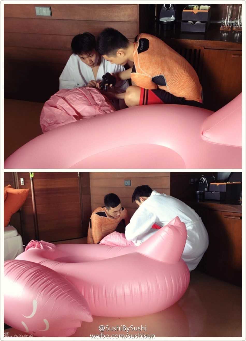 两人合力将充好气的彩色救生圈扛在肩上，准备冲向大海，背景是广阔的沙滩和蔚蓝的海水。