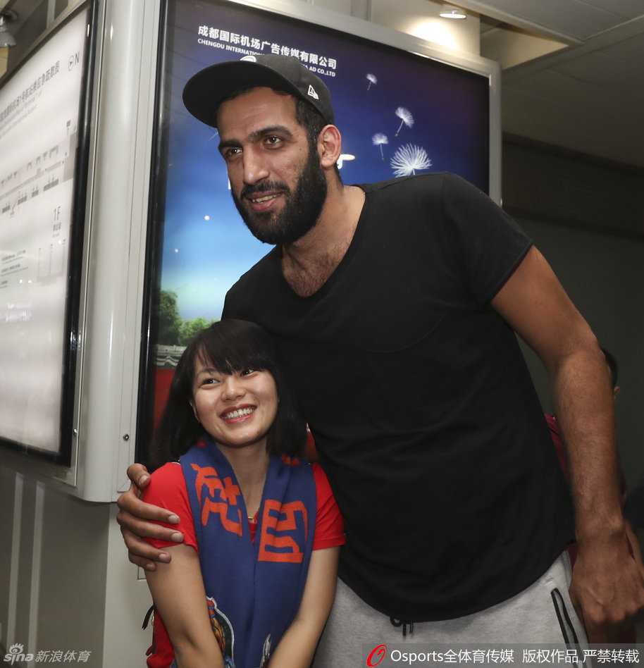 哈达迪手拿球迷递来的纪念品，低头仔细端详着上面的图案，嘴角带着一丝笑意，仿佛在与球迷分享着彼此才懂的篮球记忆。