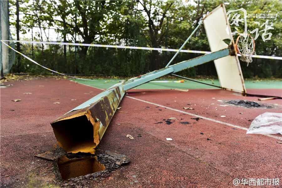 发生断裂的篮球架，根部完全与地面脱离，粗大的金属管柱扭曲变形，显示出当时承受的巨大冲击力，也暴露出设施维护的严重缺失。