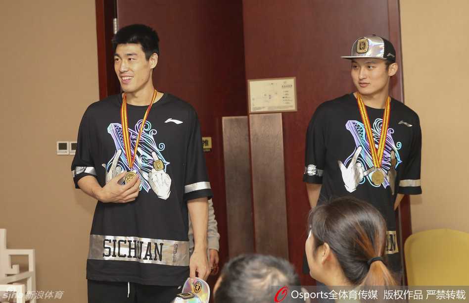 孟达与队友并肩而立，三人胸前的金牌在闪光灯下交相辉映，他们的笑容中充满了兄弟般的情谊和作为冠军队成员的自豪。
