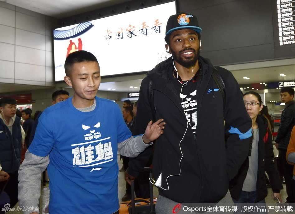 球队夺冠功臣孟达被球迷团团围住，他手持签字笔，正弯腰在一件四川队球衣上认真签名，周围是无数双充满期待的眼睛和手机镜头。