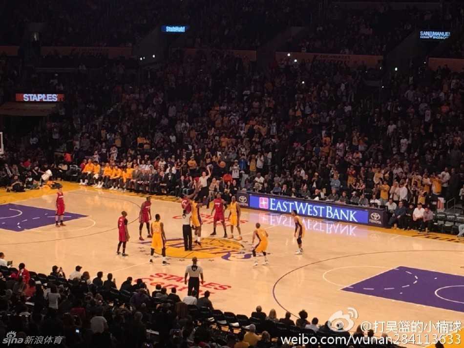 吴楠和女友在湖人队主场看台上，两人一同扭头看向球场方向，目光中充满了对比赛的专注与期待。