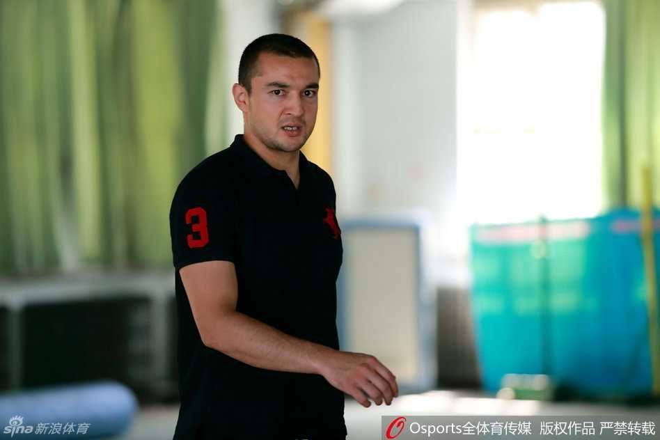 西热力江弯下腰，轻轻握住小学员的手腕，正在一对一地细致纠正他的投篮手型