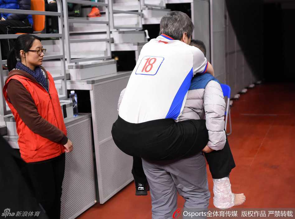 裁判坐在场边接受治疗，队医为其按压脚踝，受伤的裁判目光望向场内，心系未完成的比赛