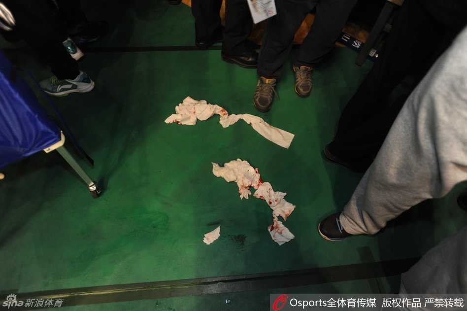 队友韩德君等人神情关切地围绕在受伤的郭艾伦身边，试图用身体筑起人墙保护他，同时焦急地向场边示意寻求担架帮助。