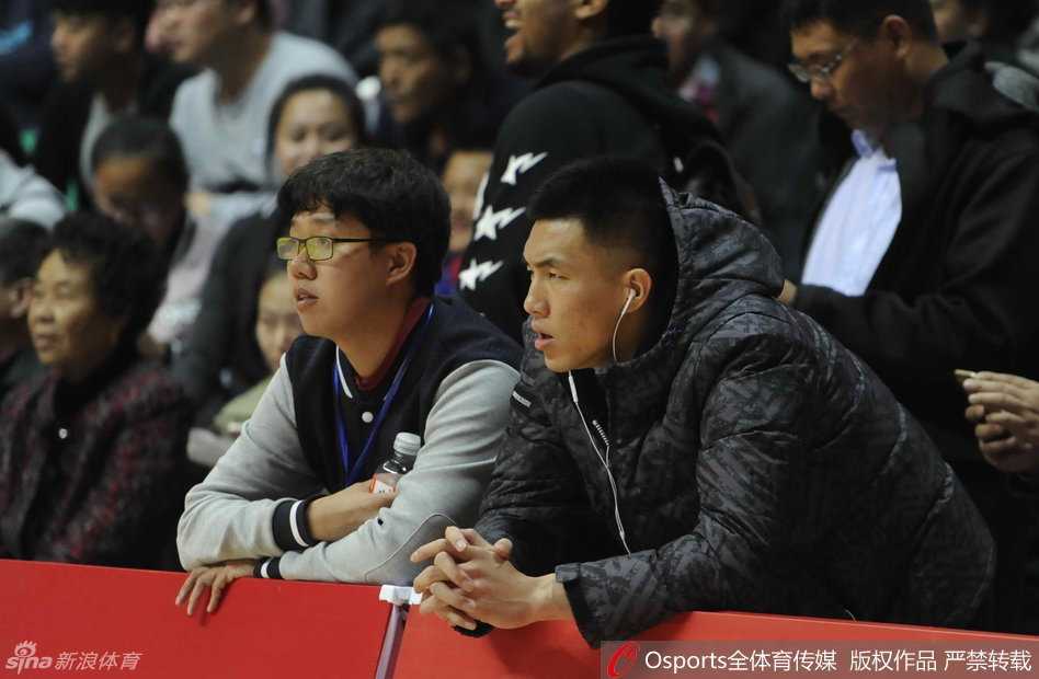 郭艾伦身披外套坐镇场边，眼神专注陷入沉思，心中翻涌着对比赛的渴望