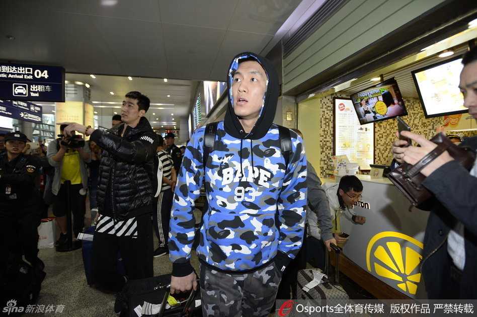 贺天举戴着口罩和帽子，将自己包裹得严严实实，但仍能看出他右手上缠着厚厚的白色绷带，在安保的陪同下快速穿过人群。