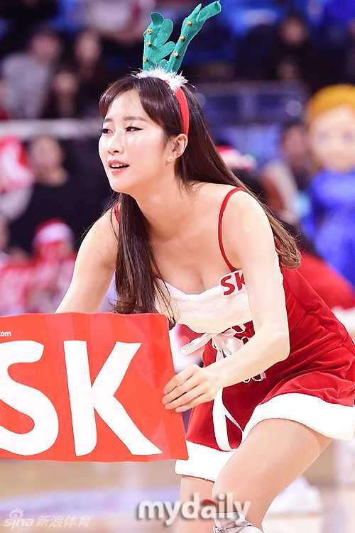 在明亮的球场灯光下，一名啦啦队员手持雪花形状的道具，神情专注地完成舞蹈定点动作，裙摆随着旋转轻轻飘起。