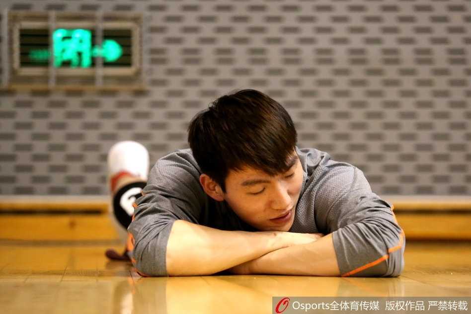 在明亮的训练馆内，一名球员正咬紧牙关，背负着沉重的杠铃进行深蹲，大腿肌肉线条分明，展现了惊人的下肢力量。