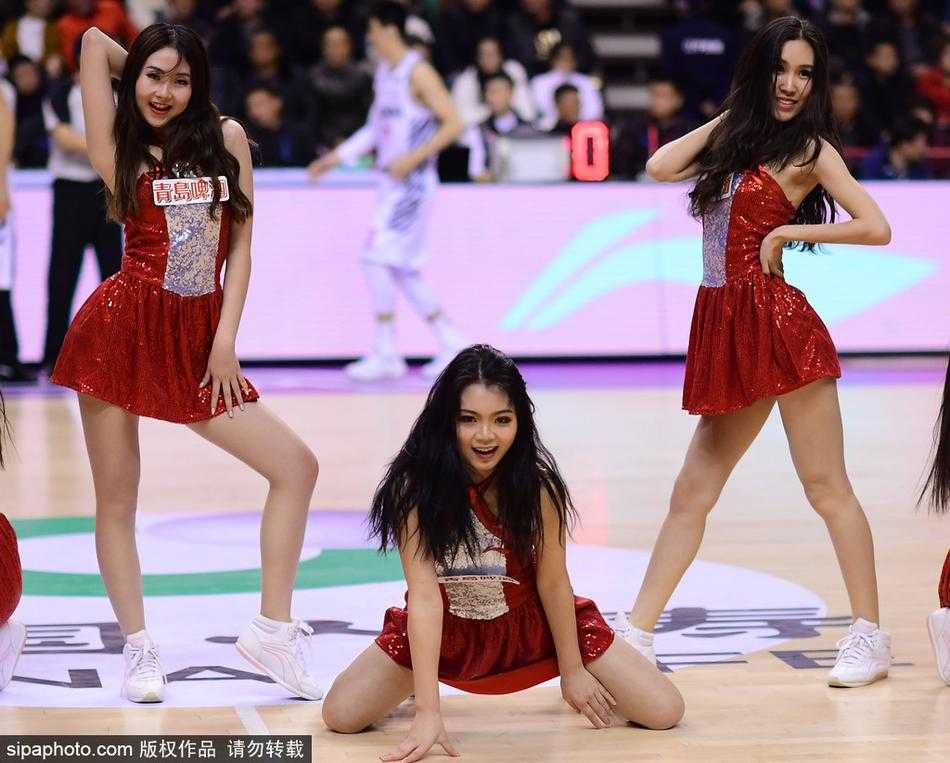 身穿红色亮片舞裙的篮球宝贝在场地中央旋转跳跃，裙摆飞扬间展现出力与美的完美结合