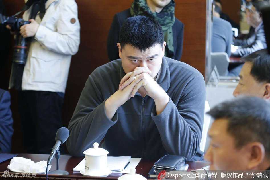 面对记者们急切伸过来的话筒，姚明微微低头倾听，眼神中充满了对媒体提问的尊重与坦诚，仿佛在用无声的语言传递改革的坚定信念。