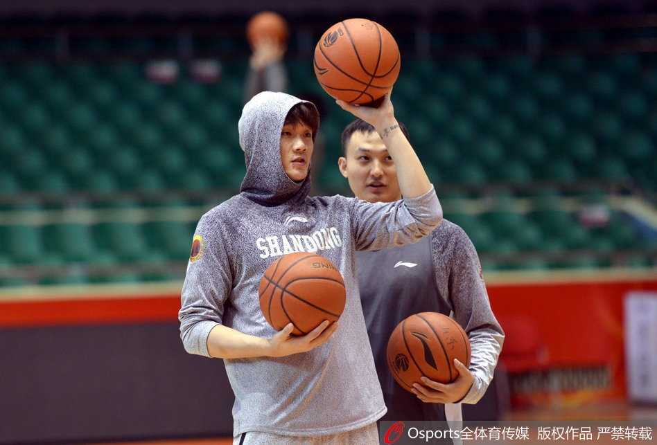 丁彦雨航在训练中试图封盖队友的投篮，动作舒展，表情专注中带着一丝笑意。