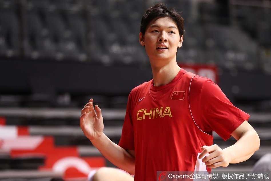 热身运动中的丁彦雨航正在进行拉伸，虽然动作有些吃力，但脸上的笑容并未褪去，反而带着一丝倔强和轻松，仿佛在享受着身体被激活的过程。