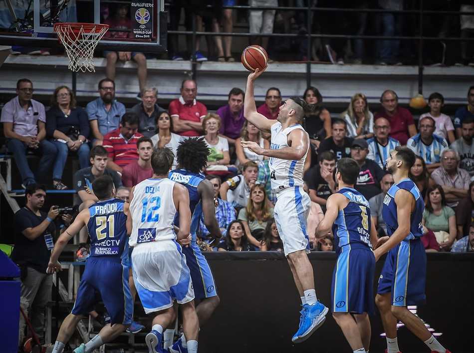 斯科拉在禁区内卡位要球，他身后的乌拉圭防守球员表情狰狞，试图用身体顶防阻止这位经验丰富的内线大师接球。