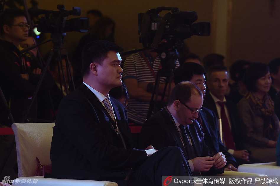 中国篮协主席姚明在发布仪式上手持话筒发言，身后的大屏幕映出会徽的图案，他神情专注而坚定