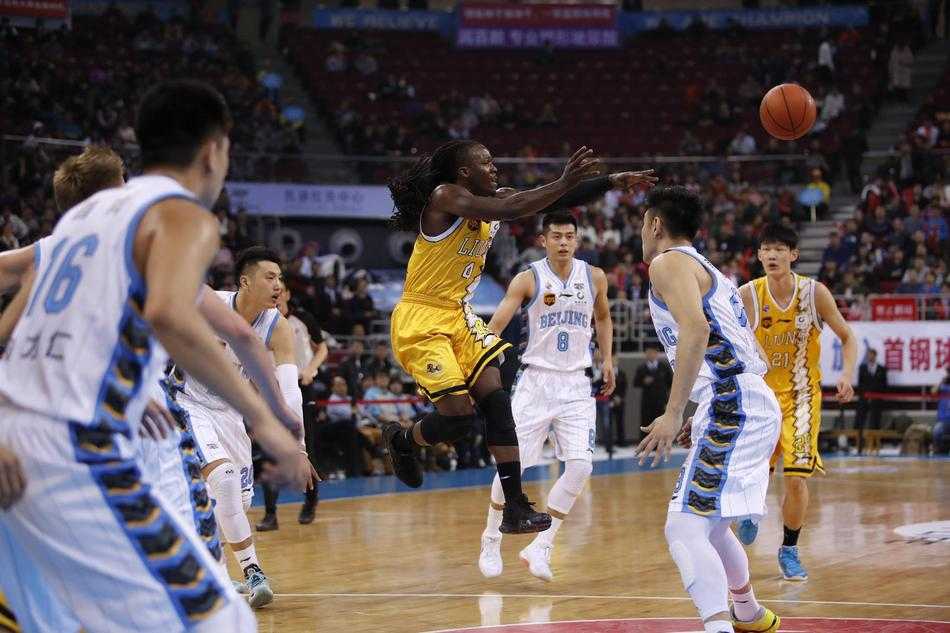 广厦队主帅李春江在场边大声指挥，他手势果断，眼神犀利，身后是密密麻麻的球迷看台，氛围紧张热烈。