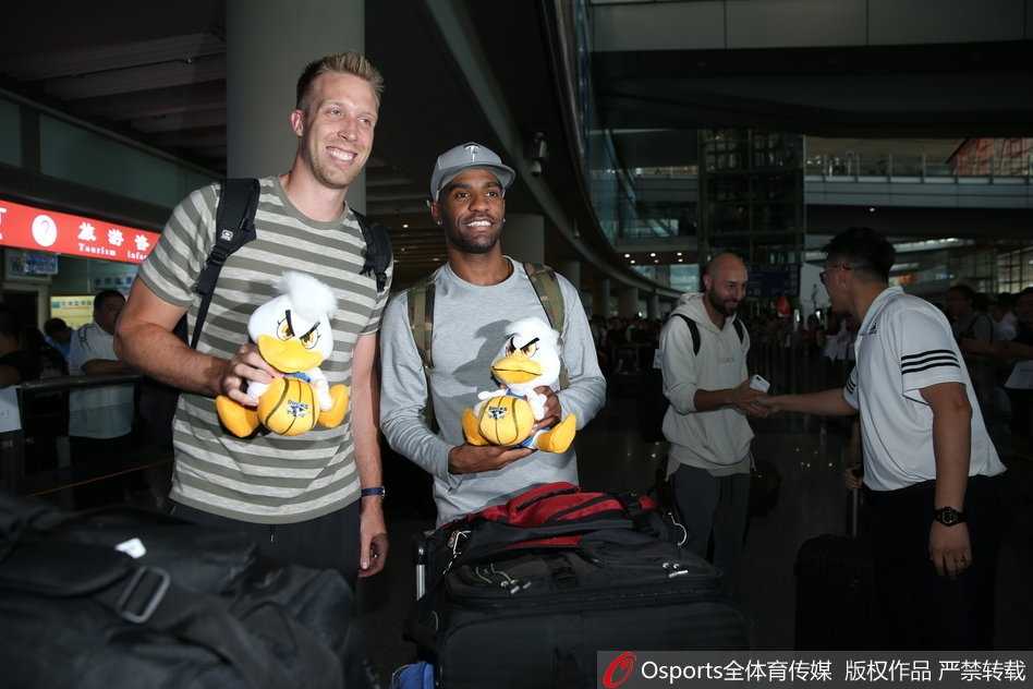 阿隆·杰克逊与汉密尔顿并肩而立，手中各自握着一只北京鸭吉祥物，两人相视而笑，仿佛在低声交流着对新赛季的无限遐想。