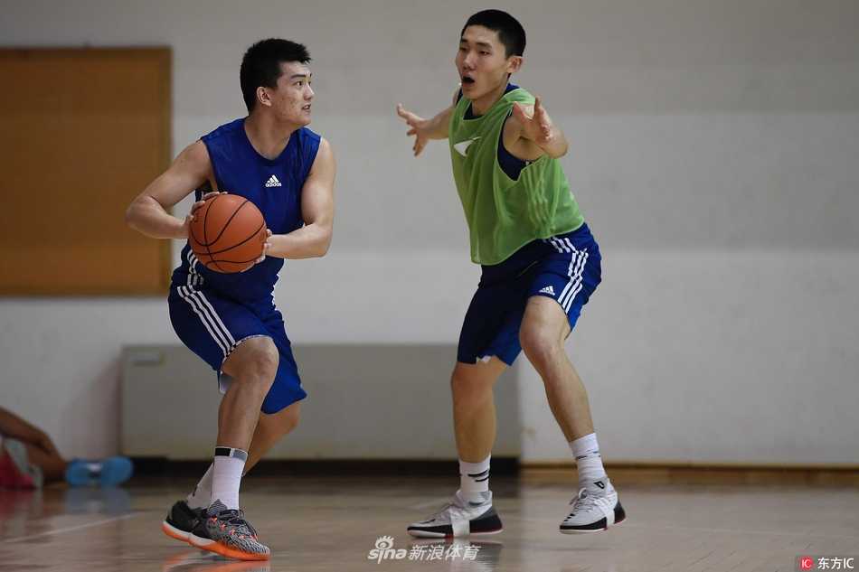 光头主帅雅尼斯神情专注，双手抱胸站在训练场中央，眼神中透露出希腊教头特有的严谨与犀利，仿佛一座雕塑般审视着场上的每一位弟子。