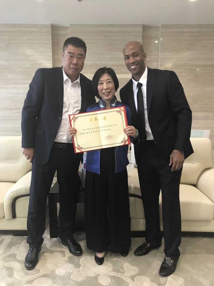 在摆满了荣誉奖杯和篮球的俱乐部背景板前，张阿姨接过北控俱乐部颁发的捐赠证书，她双手捧着证书，脸上露出了谦逊而满足的微笑。