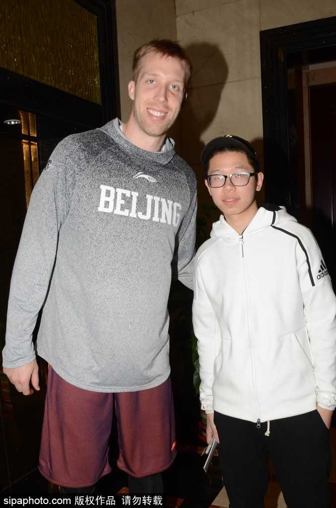 丘天为球迷签名后互动交流，高大身材与亲切姿态形成反差萌，现场氛围热烈有序