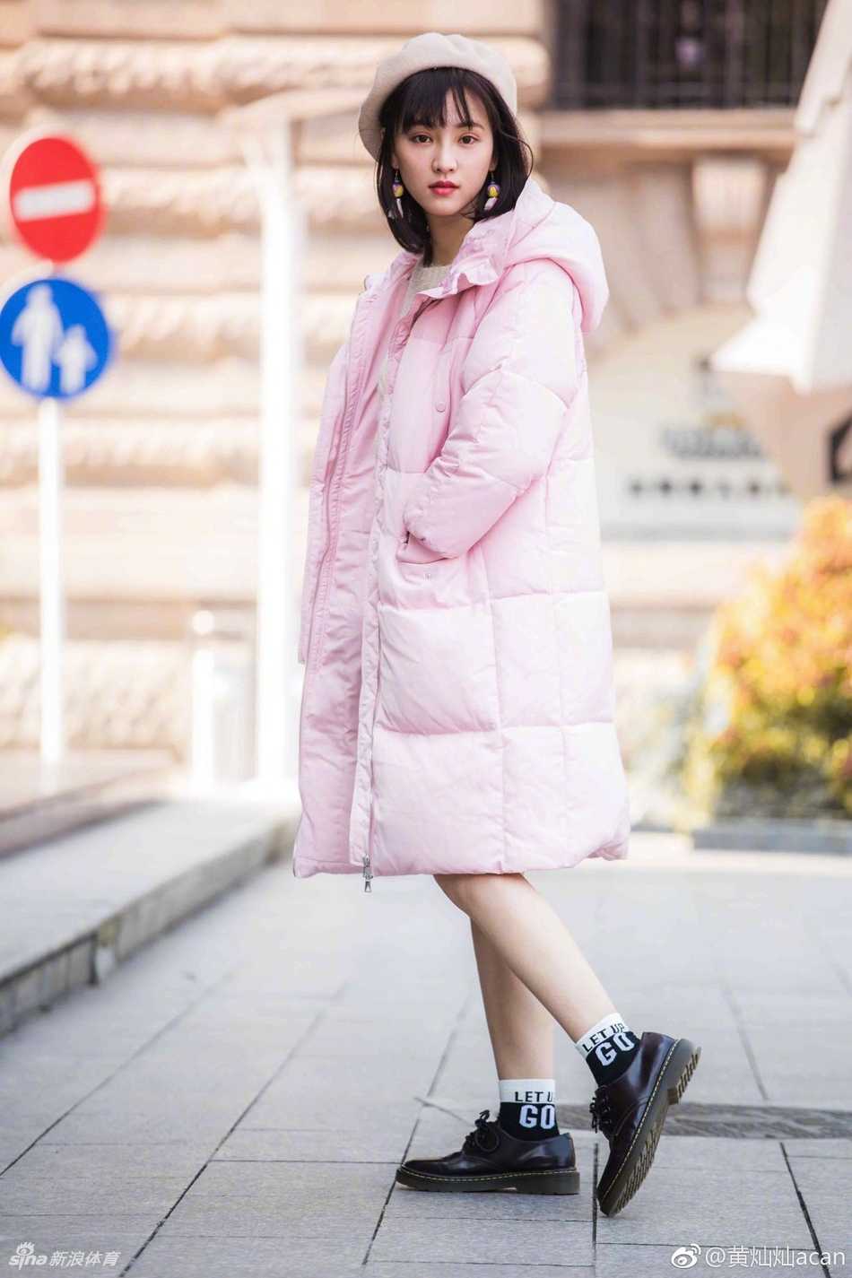 黄灿灿穿着休闲外套坐在场边，双手交叠搭在膝盖上，嘴角带着浅浅笑意，仿佛正在和场上的朋友交谈。