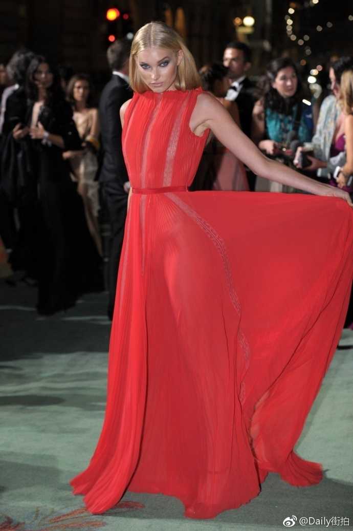 活动现场的艾尔莎手拿精致手包，红裙的剪裁完美展现了她的直角肩和天鹅颈，回眸一笑间，优雅与自信浑然天成。