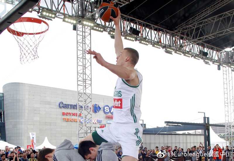 欧冠传奇球星西奥·帕帕卢卡斯在表演赛中俯身运球，眼神中带着顽童般的专注，与他对位的特殊奥林匹克小球员则兴奋地张开双臂防守。