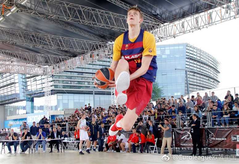 一位身穿土耳其球队外套的小球迷踮起脚尖，目光穿越人群，紧紧追随着场内正在进行的趣味投篮赛，纯真的脸上写满了对篮球世界的向往。