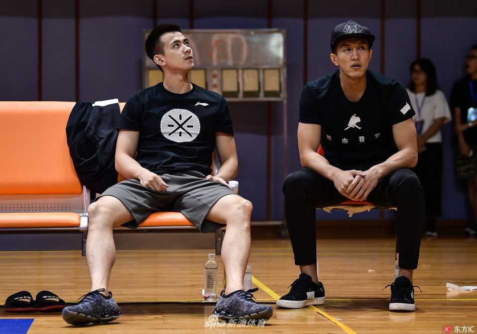 郭艾伦神情专注地坐在场边，身着便装观看着场内激烈的比赛，眼神中透露出对赛场的渴望