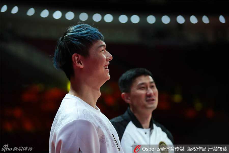 王哲林与杜锋在场边谈笑风生，王哲林笑得眼睛眯成了一条缝，用手捂着脸，杜锋则面带微笑地看着他，气氛轻松愉悦。