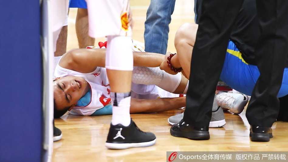 被抱到场边的赵继伟躺在蓝色的软垫上，左脚踝已经缠上了厚厚的冰袋进行紧急冰敷。他双眼望向赛场方向，眼神中满是对比赛的留恋和对自己伤情的担忧，队医则在一旁全程守护，密切关注着他的反应。