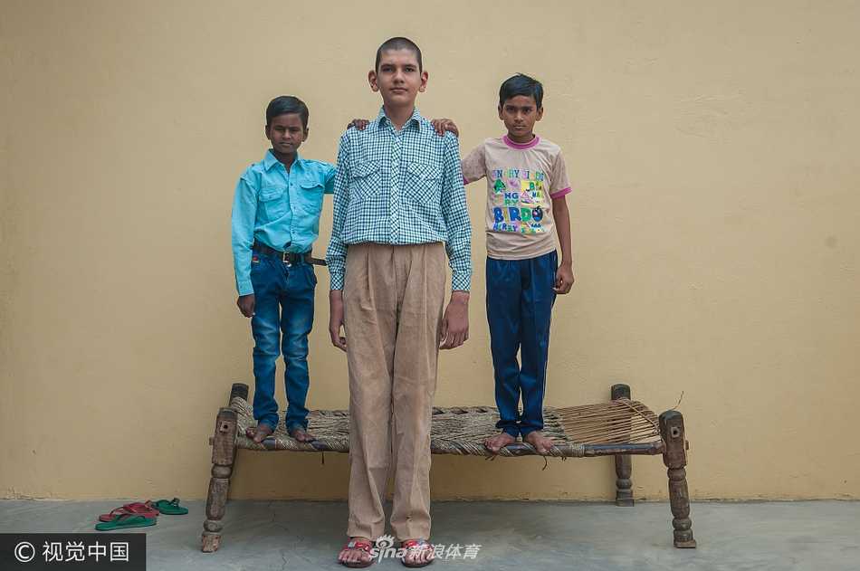 校园里的“鹤立鸡群”：八岁的卡兰穿着校服站在队列中，他的身高远超身旁的同学，仿佛一个高年级学生误入了低年级的队伍，画面既震撼又带着几分童趣。