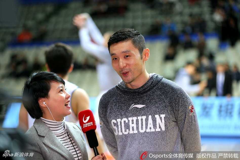 刘炜与上海队的老友在赛场边亲切交谈，眼神交汇中充满了无需言语的默契与兄弟情深，背景是源深体育馆熟悉的灯光。