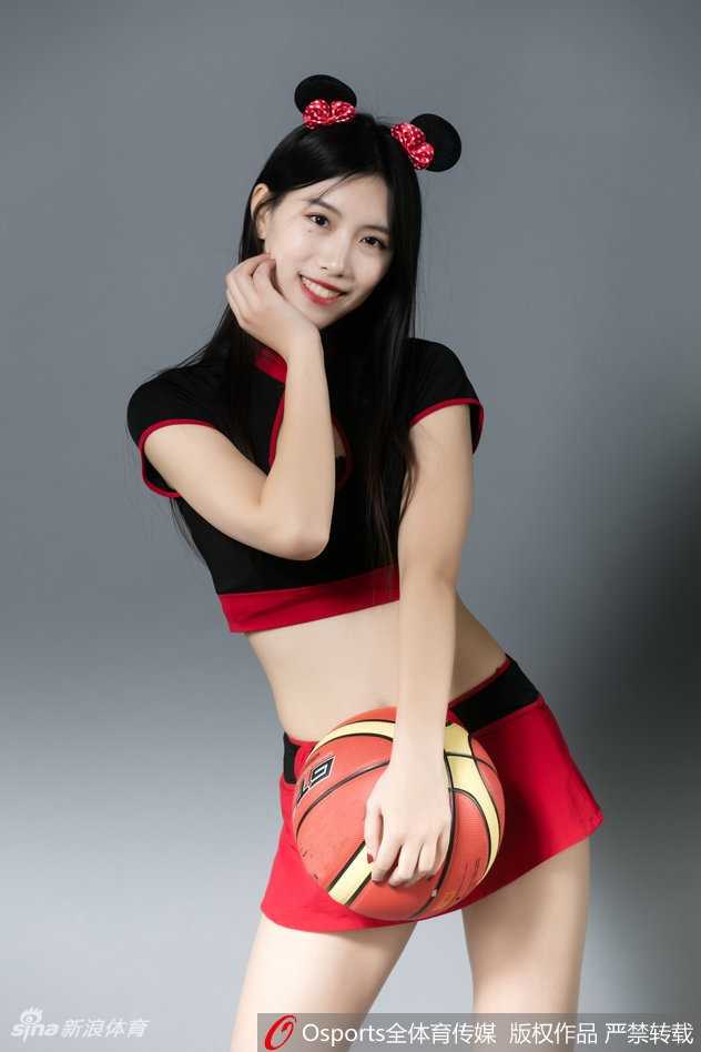 一位篮球宝贝侧身回眸，乌黑的长发上戴着精致的米奇耳朵发卡，眼神俏皮灵动，背景是模糊的看台人浪