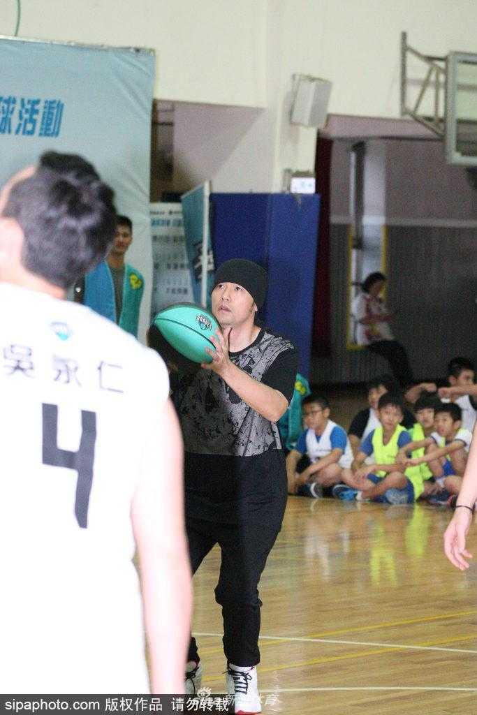 活动接近尾声，周杰伦站在场地中央与几十名身穿蓝色球衣的孩子们合影，他依然戴着那条标志性的黑色头巾，双手插腰，被孩子们簇拥着，画面定格在这个充满爱心与活力的夏日午后。