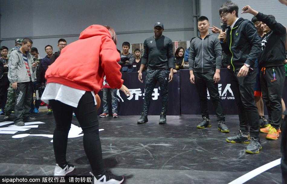 哈德森出手三分后眼神紧盯篮球轨迹，表情专注，背景里的沈阳球迷纷纷举起手机记录下这一瞬间。