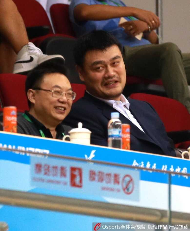 当比赛进入暂停时段，姚明与身旁的友人不经意间的交谈，脸上挂着轻松写意的微笑，这和谐的一幕宛如球场边最亮眼的风景线。