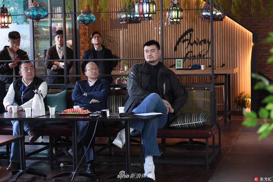 姚明坐在媒体沙龙活动的前排座位上，双手交叉置于身前，嘴角带着一丝微笑，认真倾听旁边裁判的解读发言。