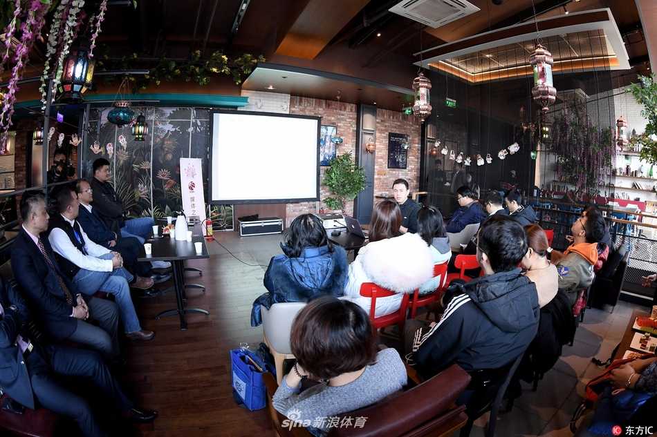 姚明在会议间隙与身旁的工作人员轻松交谈，他身体微微前倾，表情亲和，展现了篮协主席与基层工作者之间的良好互动。