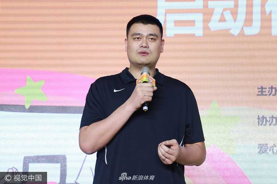 在启动仪式的背景板前，姚明弯下腰身，耐心地为一名来自希望小学的小球员整理衣领，他的眼神专注而温柔，小球员则昂着头，满怀敬仰地看着这位篮球巨人，画面定格在这一刻，充满了温情与希望。