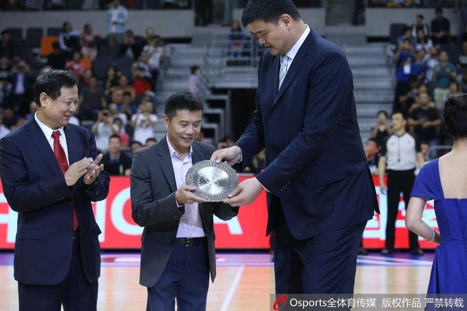 陈海涛（中）代父领奖时，脸上洋溢着自豪与感动，身后的大屏幕上播放着宏远名宿们的祝福，这一刻家族的荣耀与篮球的传承交织在一起。