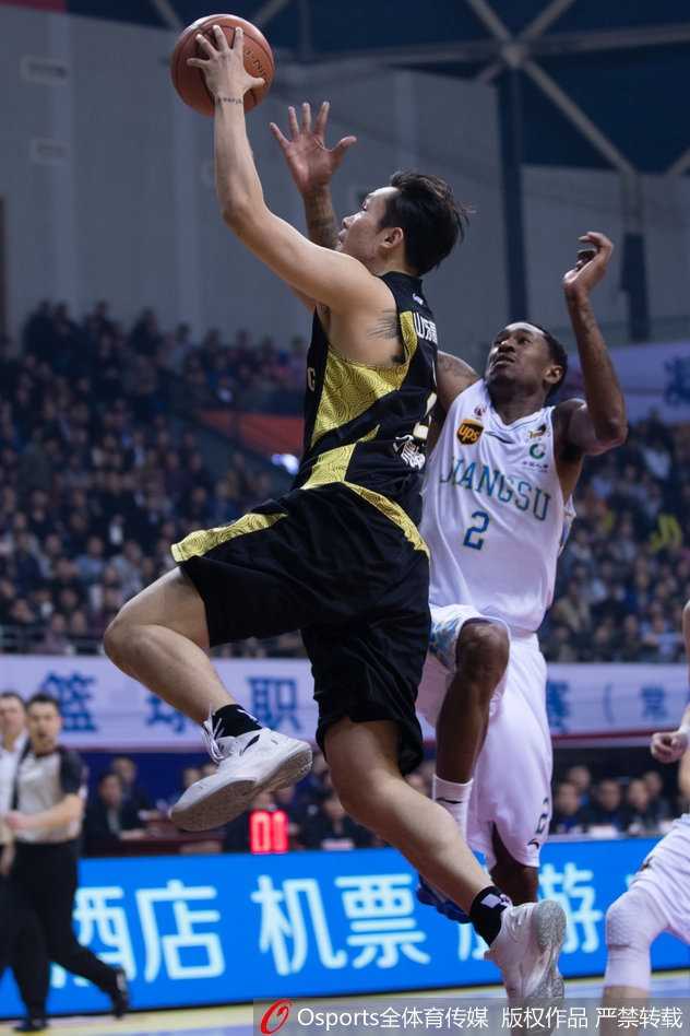 丁彦雨航在严密防守下强行突破，身体在空中与对手发生碰撞，依然奋力将球抛向篮筐，裁判哨响瞬间。