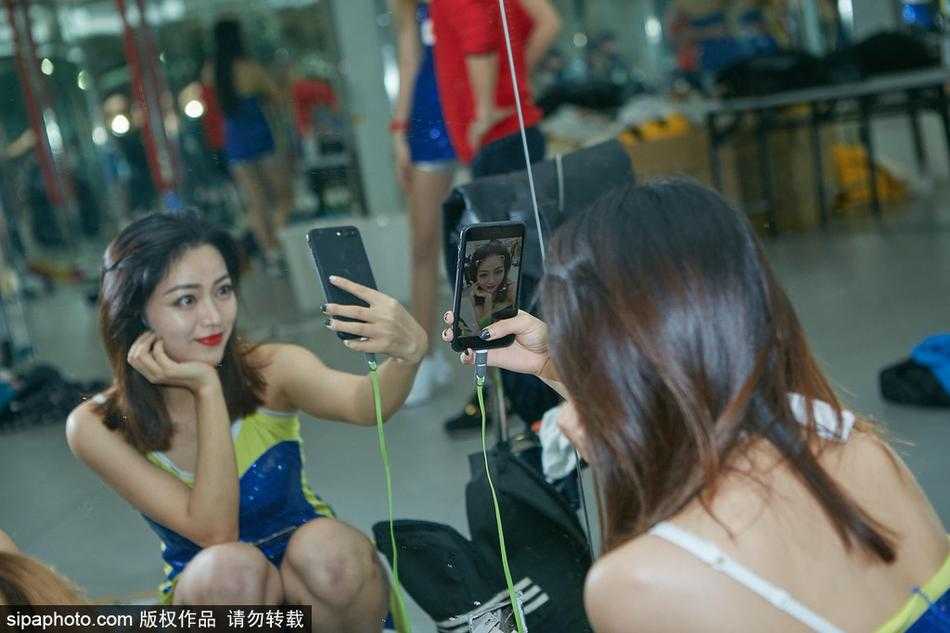 排练间隙的轻松互动，两名队员相视而笑，手中的花球映衬着青春的脸庞，汗水与笑容交织成赛前最美的风景