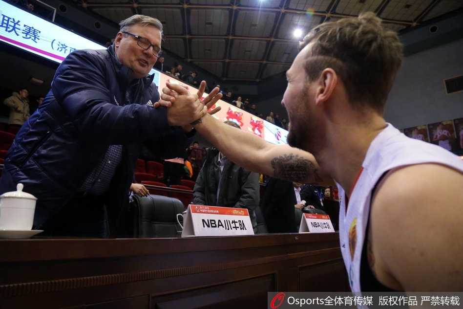 王治郅、丁彦雨航和小尼尔森三人同框，大郅双手插袋气定神闲，小丁侧耳倾听，小尼尔森则侃侃而谈，背景里的球馆灯光为这一刻镀上了温暖的光晕。