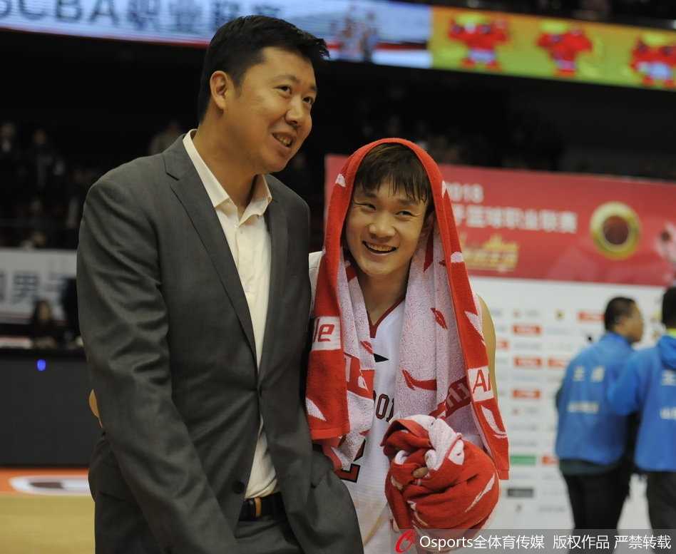 丁彦雨航俯身凑近小尼尔森，双手撑膝认真倾听，小尼尔森则用手比划着，像是在面授机宜，指点着这位年轻人的未来之路。