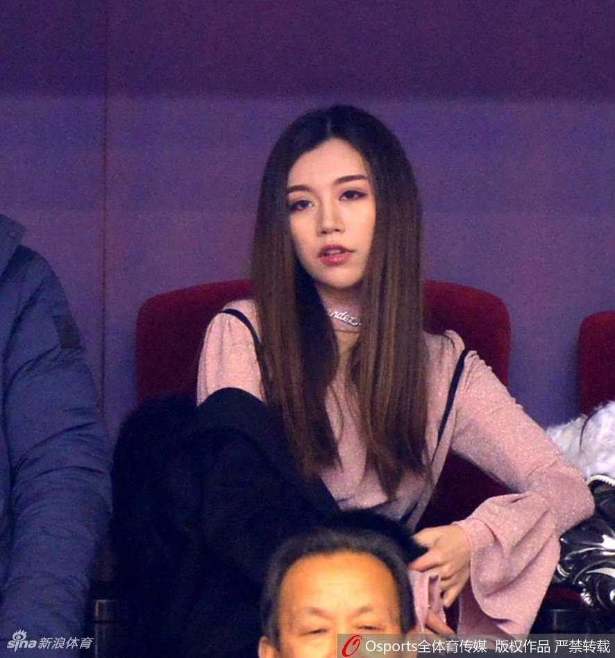 丁彦雨航女友手持加油棒，在人群中静静站立，尽管戴着口罩，但弯成月牙的眼睛透露出她对比赛的投入和对胜利的渴望。