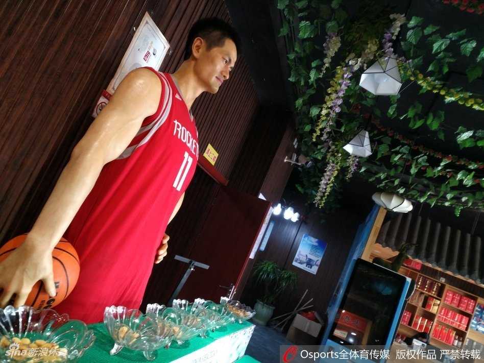 近距离特写这尊蜡像的上半身，蜡像的面部表情栩栩如生，眼神温和地望向前方，火箭队球衣的纹理和号码都清晰可见，制作工艺相当考究