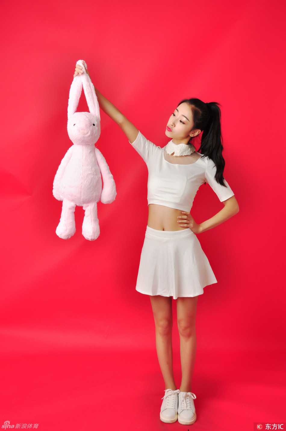 两位队员并肩而坐，白色短裙衬托出修长美腿，一人调皮比耶，一人温柔浅笑，闺蜜般的默契感溢出画面