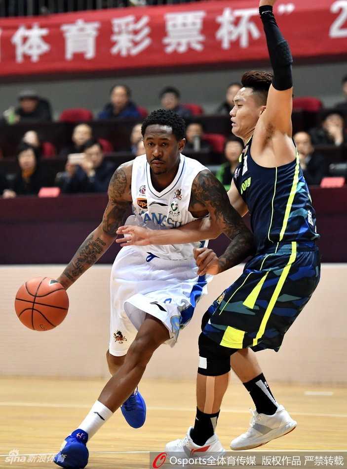 广东宏远队球员在高速突破中面对江苏肯帝亚两人的严密夹防，眼神坚毅寻找传球路线，空气中弥漫着季后赛级别的对抗火药味。